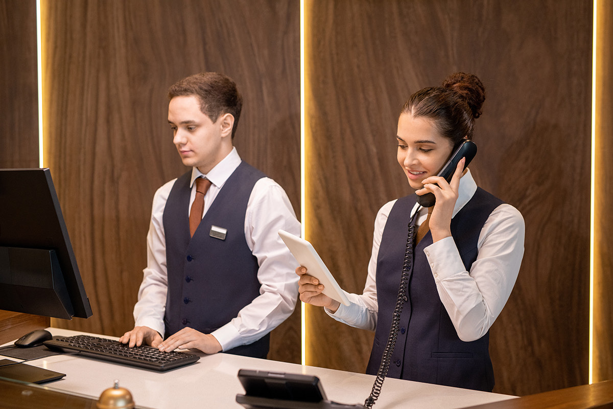 Hotel receptionists answering a call with an IP phone and tablet