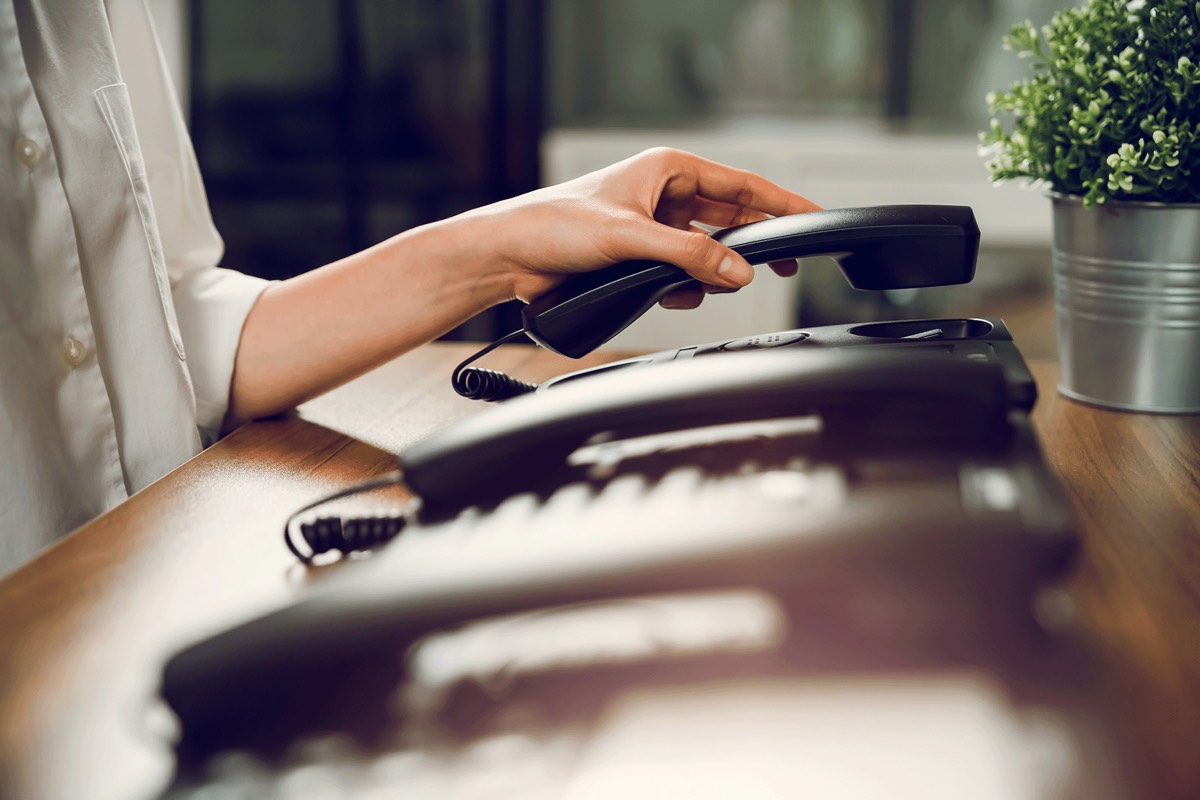 Mano che solleva un telefono IP alla reception